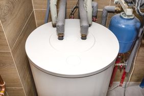 Water heater tank with plumbing connections in a utility room