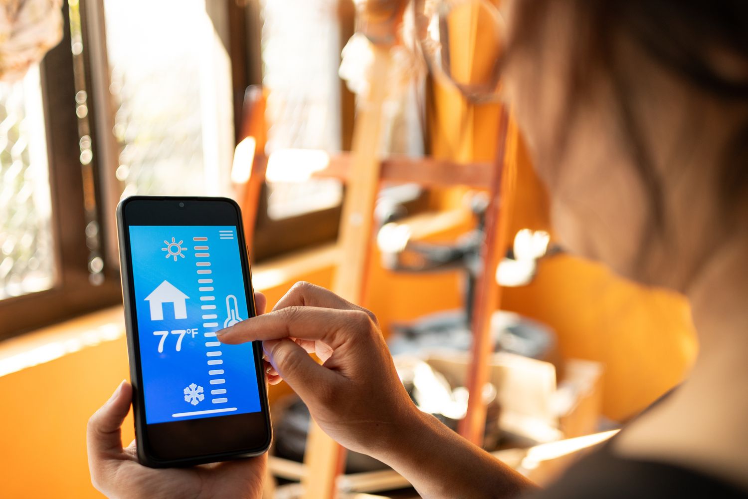 Young woman indoors using an app to control the temperature of her home in Fahrenheit