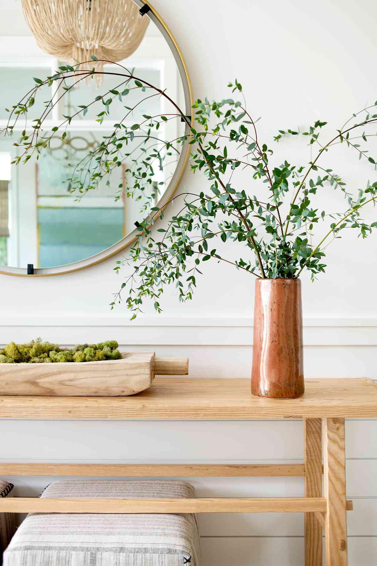 circular mirror with green plant in vase on table