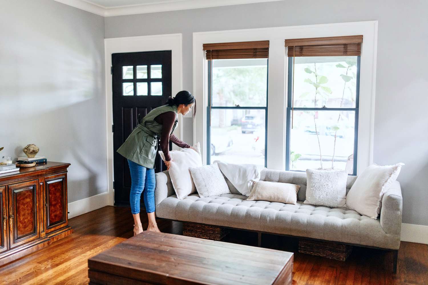 A person adjusts pillows on a couch in a living room