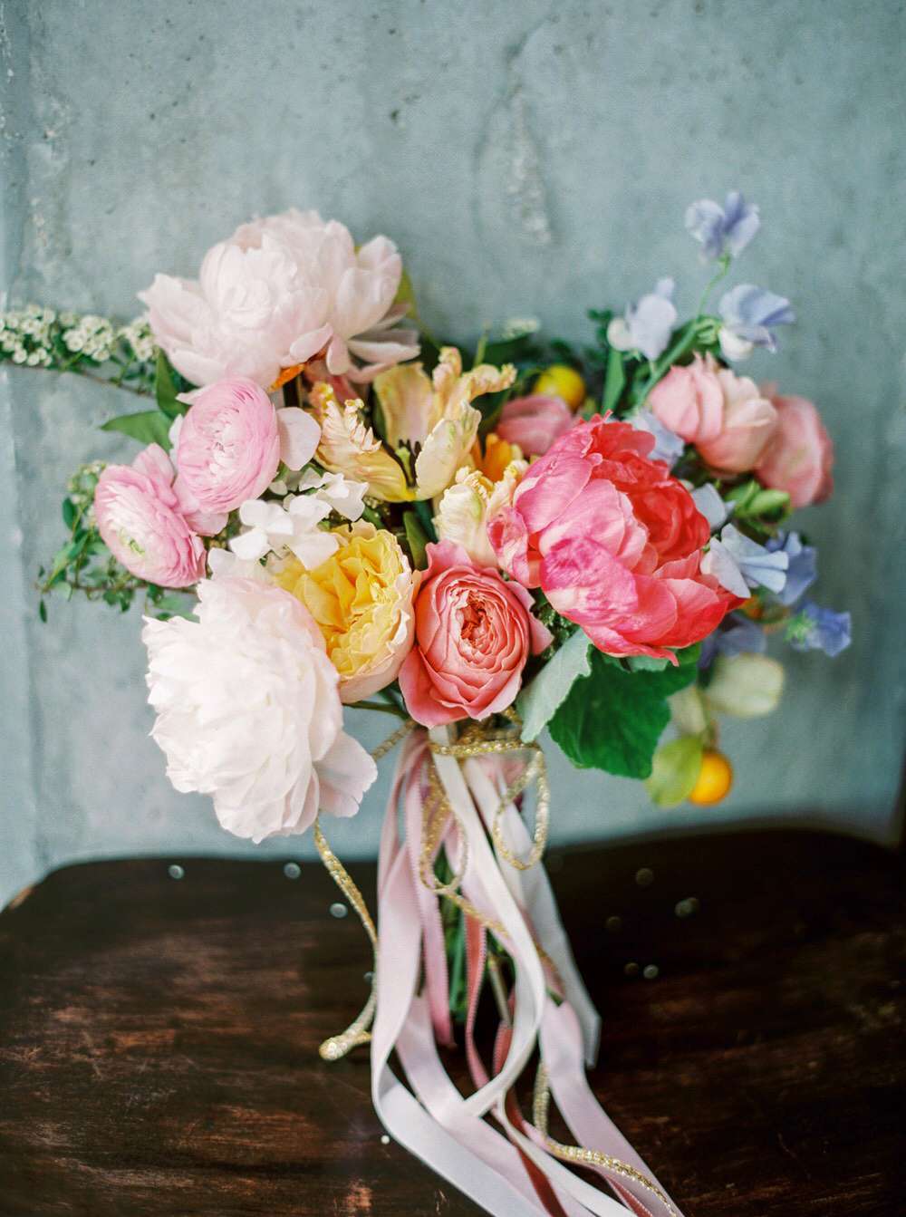 pink-and-white peony bouquet with blush ranunculus, yellow roses, and purple sweet peas