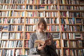 A woman reading in front of a large bookshelf