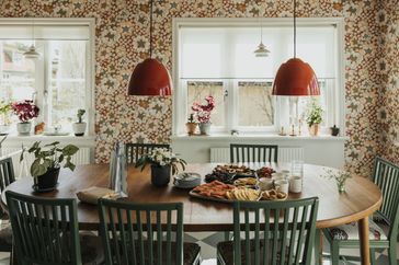 A dining table set with food and drinks surrounded by green chairs in a welllit room