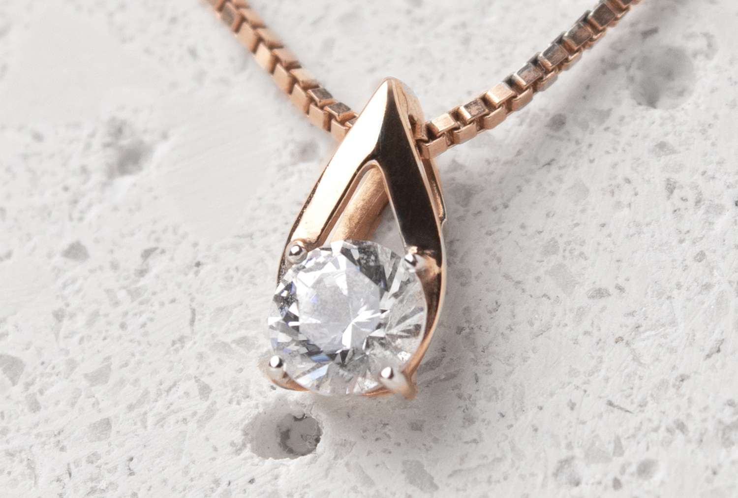 A diamond pendant necklace on a textured background