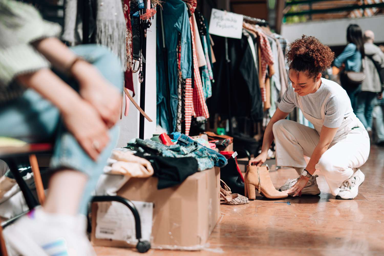 A woman sorting items at a clothing stall in a market setting