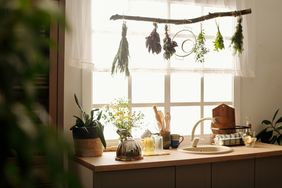 A cozy kitchen counter with spices hanging to dry above the sink various herbs and kitchenware on the countertop