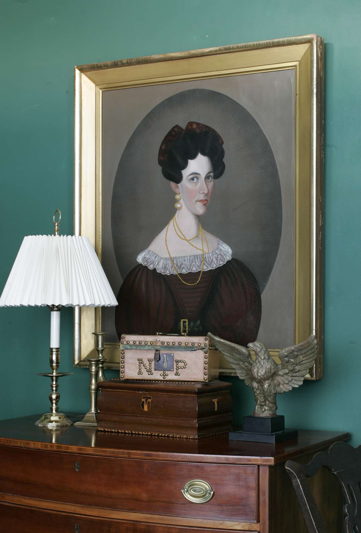 A painted portrait of a woman above Hepplewhite New England bow-front cherry chest