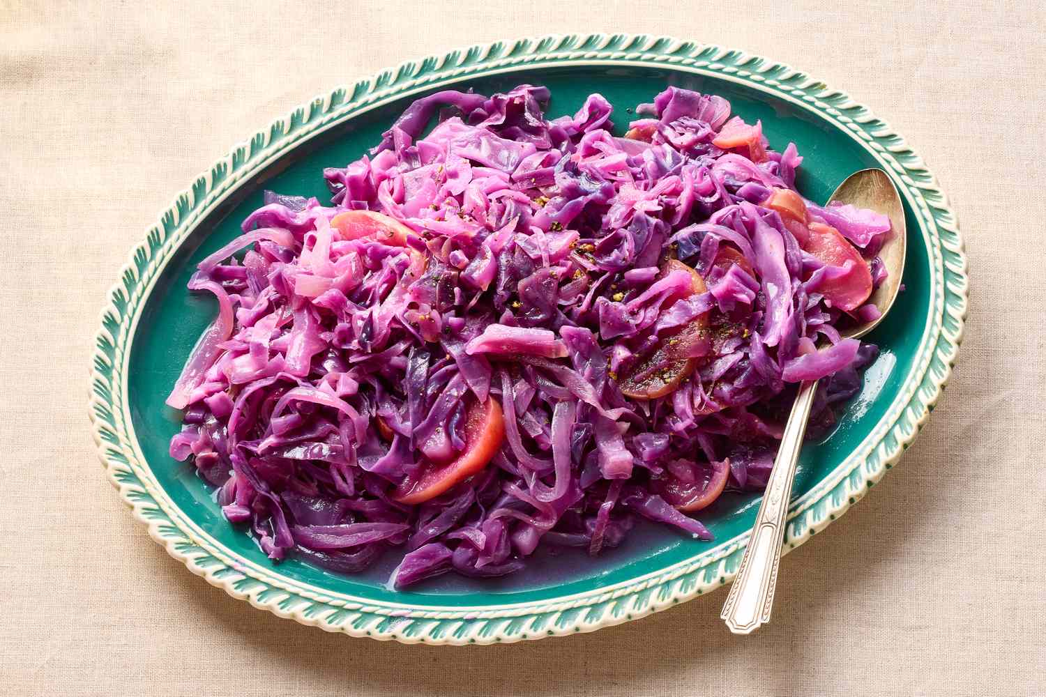Braised red cabbage with apple and onion served on a platter with a spoon