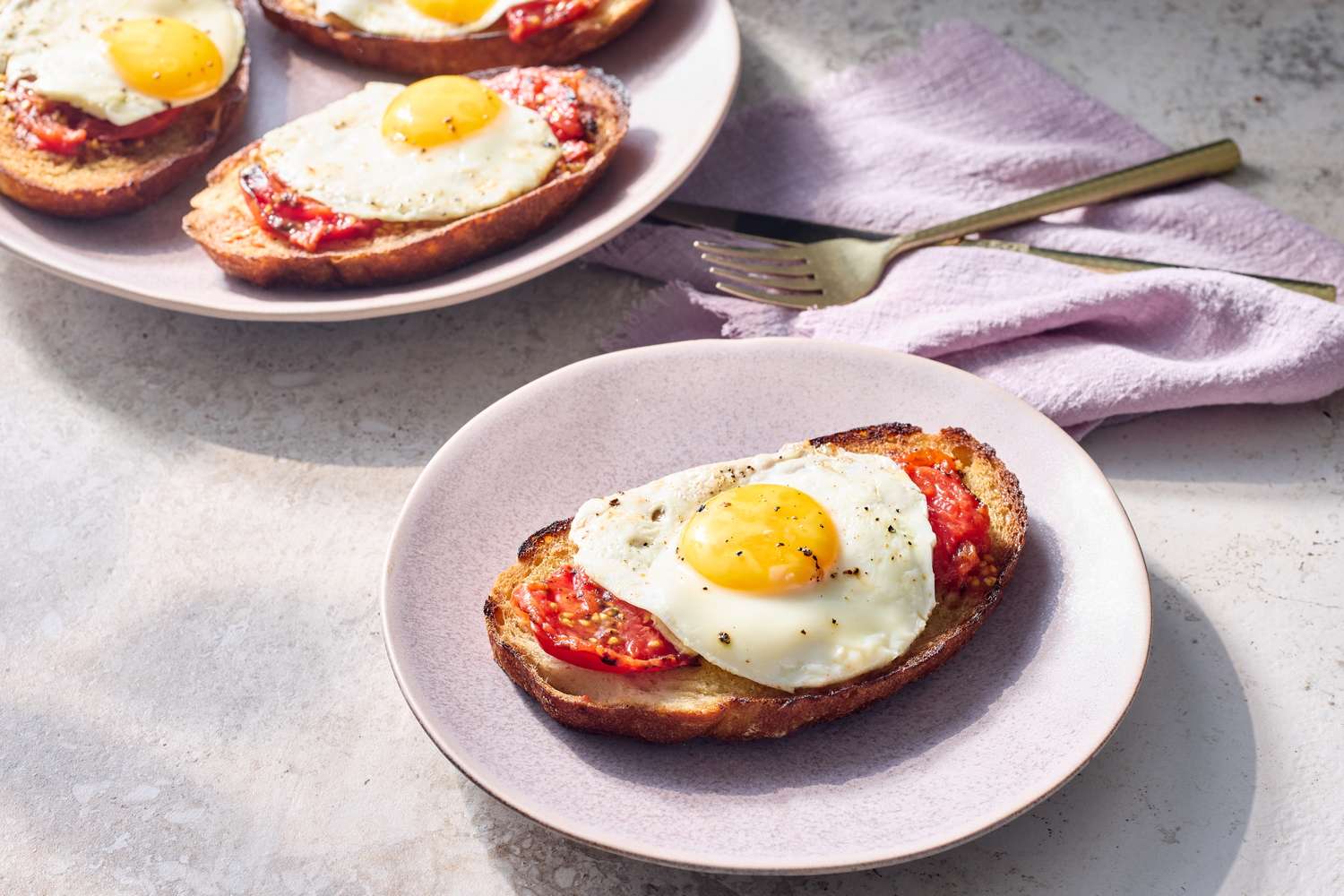 Plates of toast topped with charred tomatoes and fried eggs