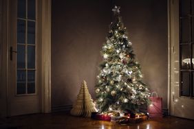 Lit Christmas tree indoors with decorations and gifts underneath