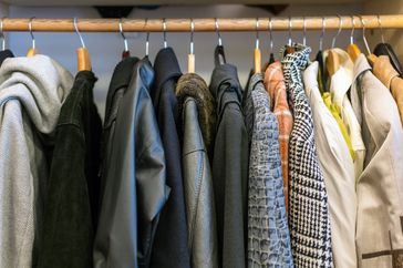Wardrobe full of different color, material and texture clothes, accessories in the closet