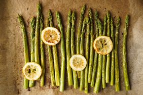 Asparagus spears roasted with slices of lemon placed on a baking sheet