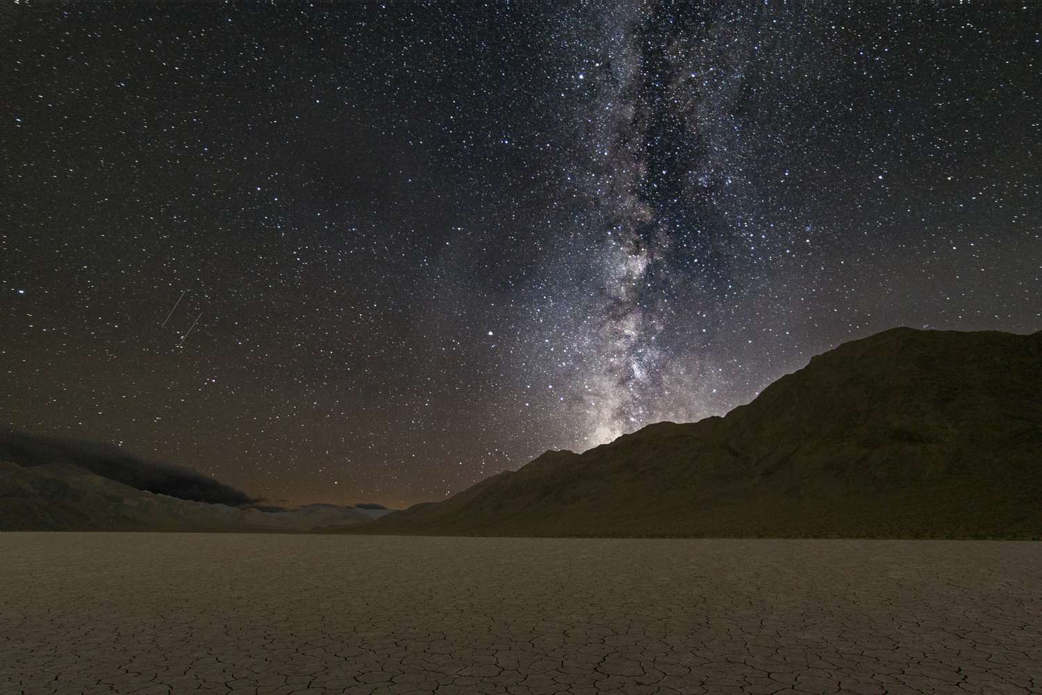 Night sky with the Milky Way visible over a mountainous desert landscape