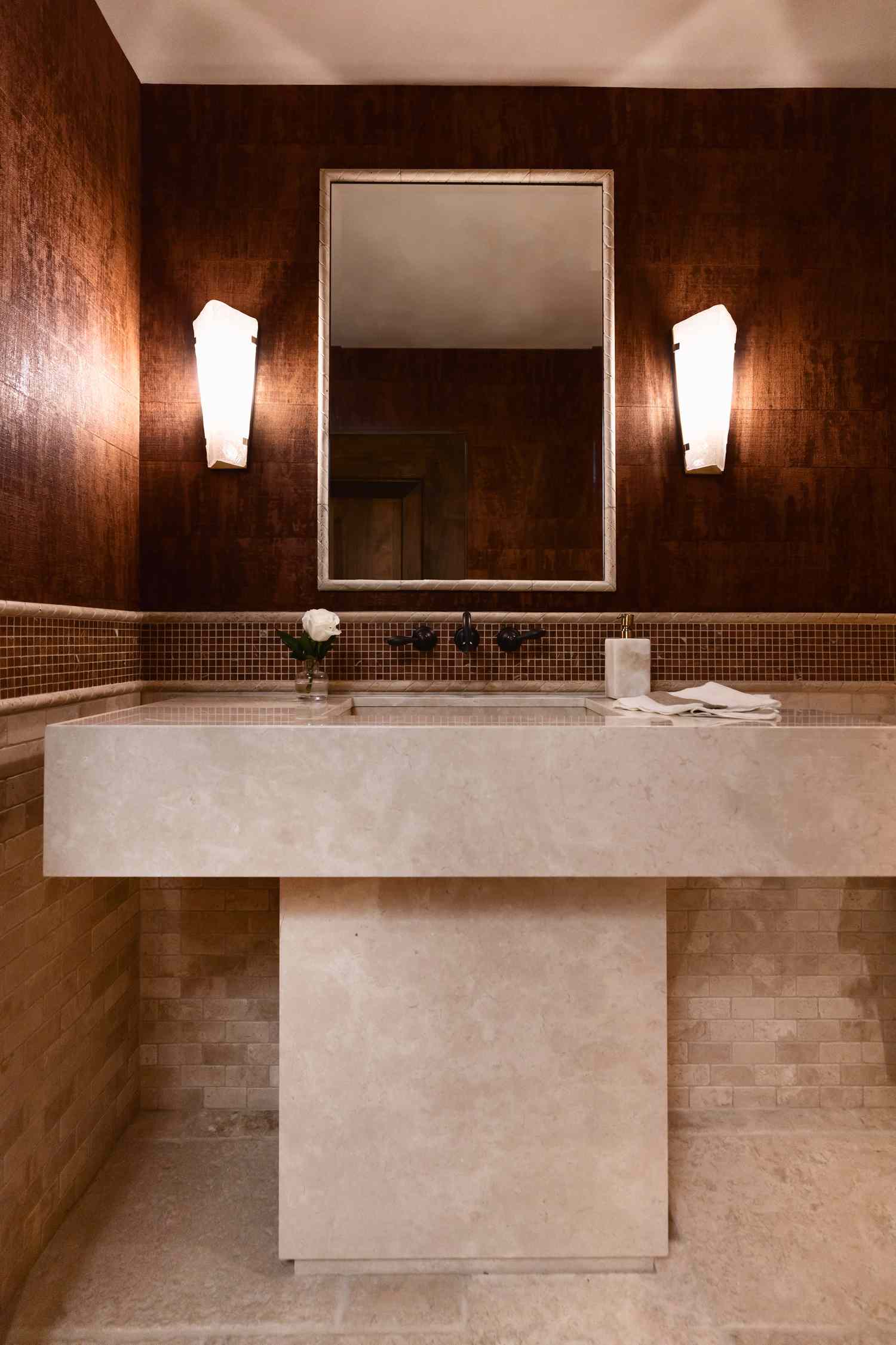 a neutral powder bath with modern marble sink and geometric sconces
