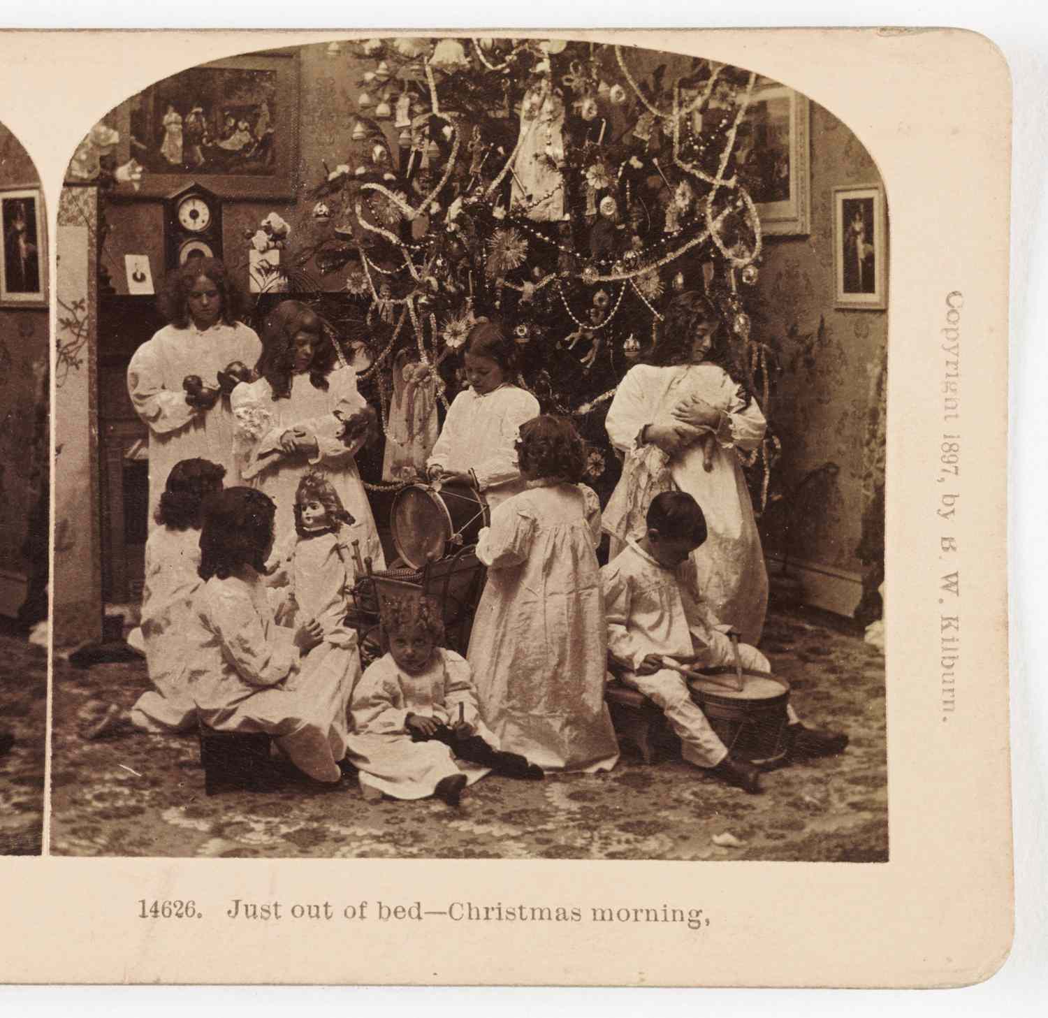 Children gathered around a Christmas tree on Christmas morning engaged in various activities
