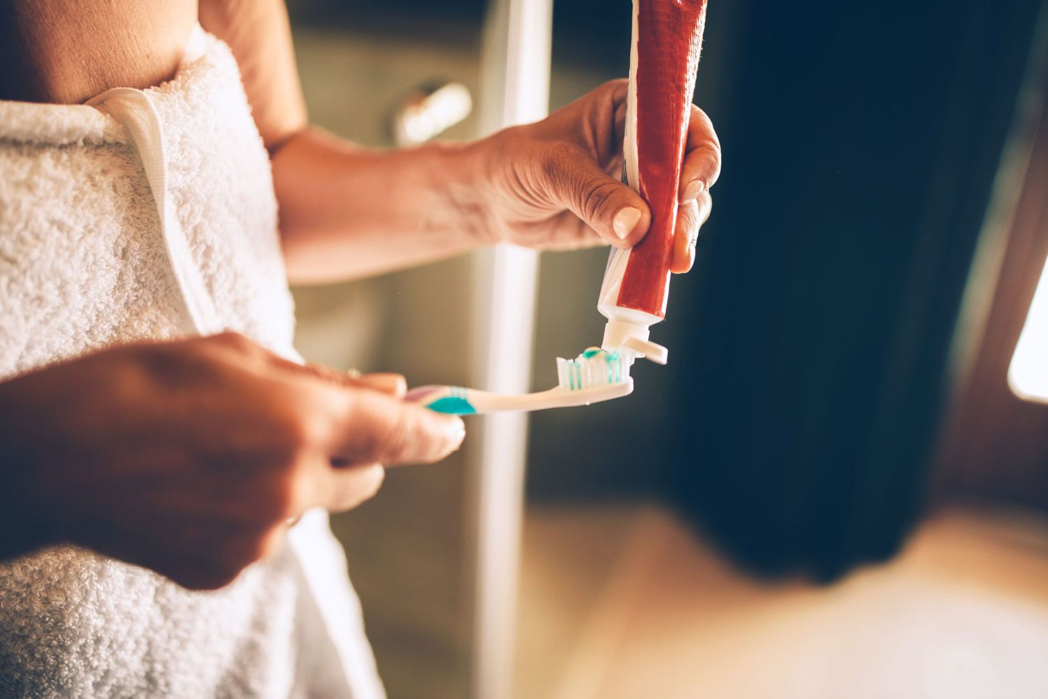 woman applying toothpaste to toothbrush