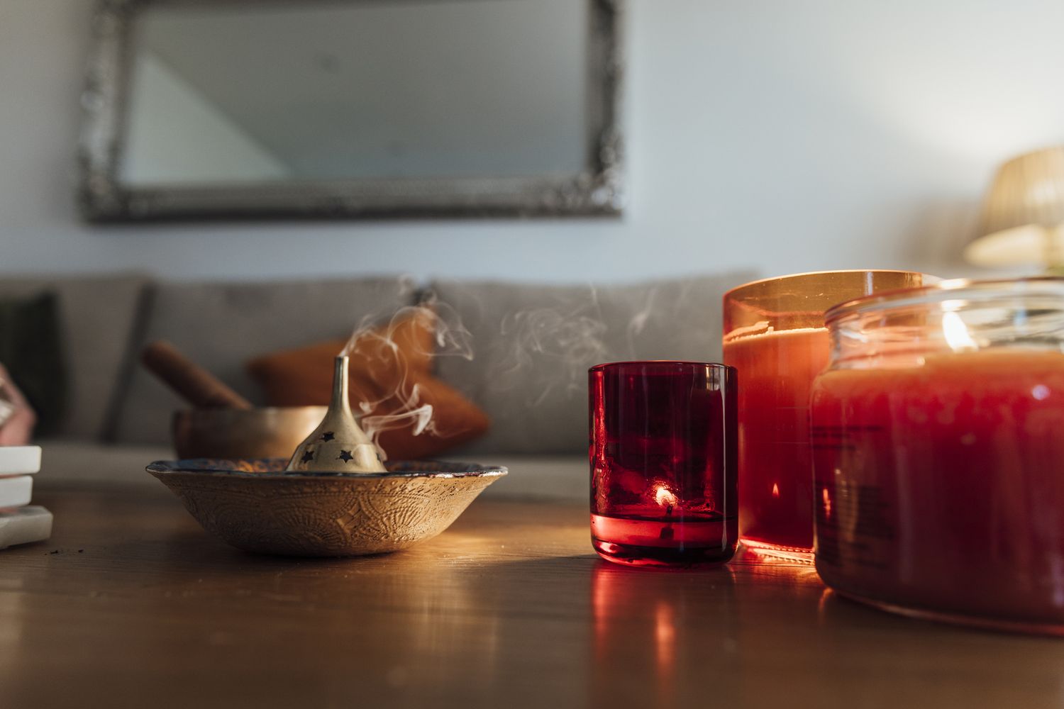 Burning candles and a smoking incense stick on a table indoors