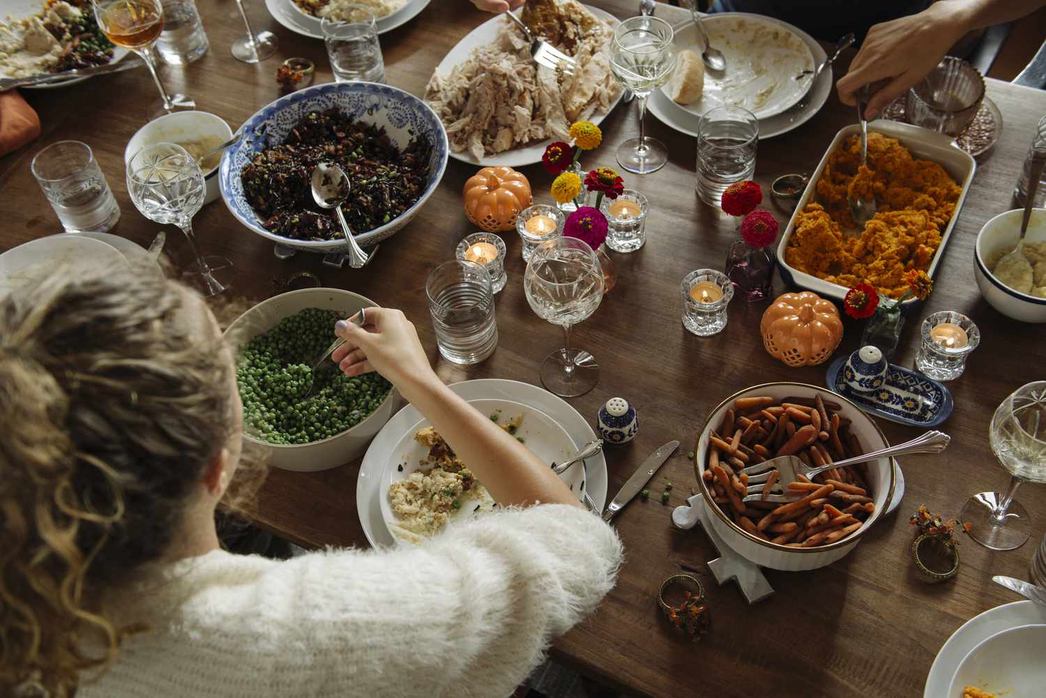 A dining table with various dishes served and people sharing food showcasing a meal gathering scene