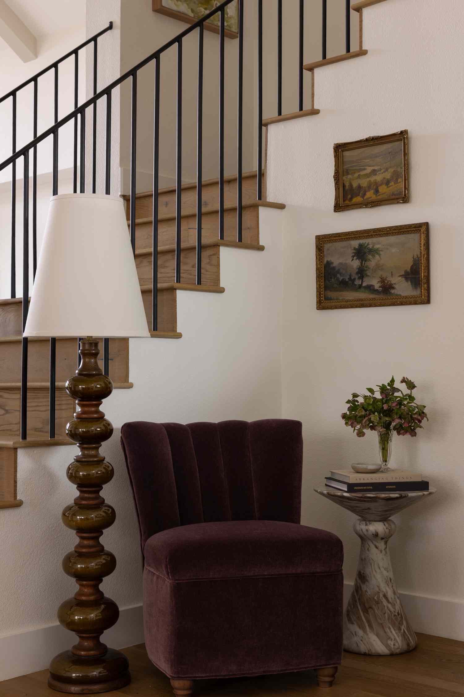 A cozy corner with a chair lamp and small table next to a staircase