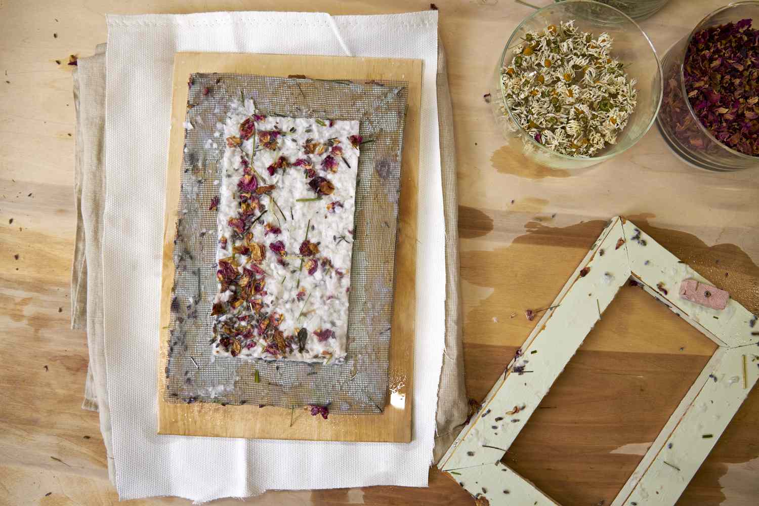 Handmade paper with dried rose petals and chamomile flowers on a wooden frame