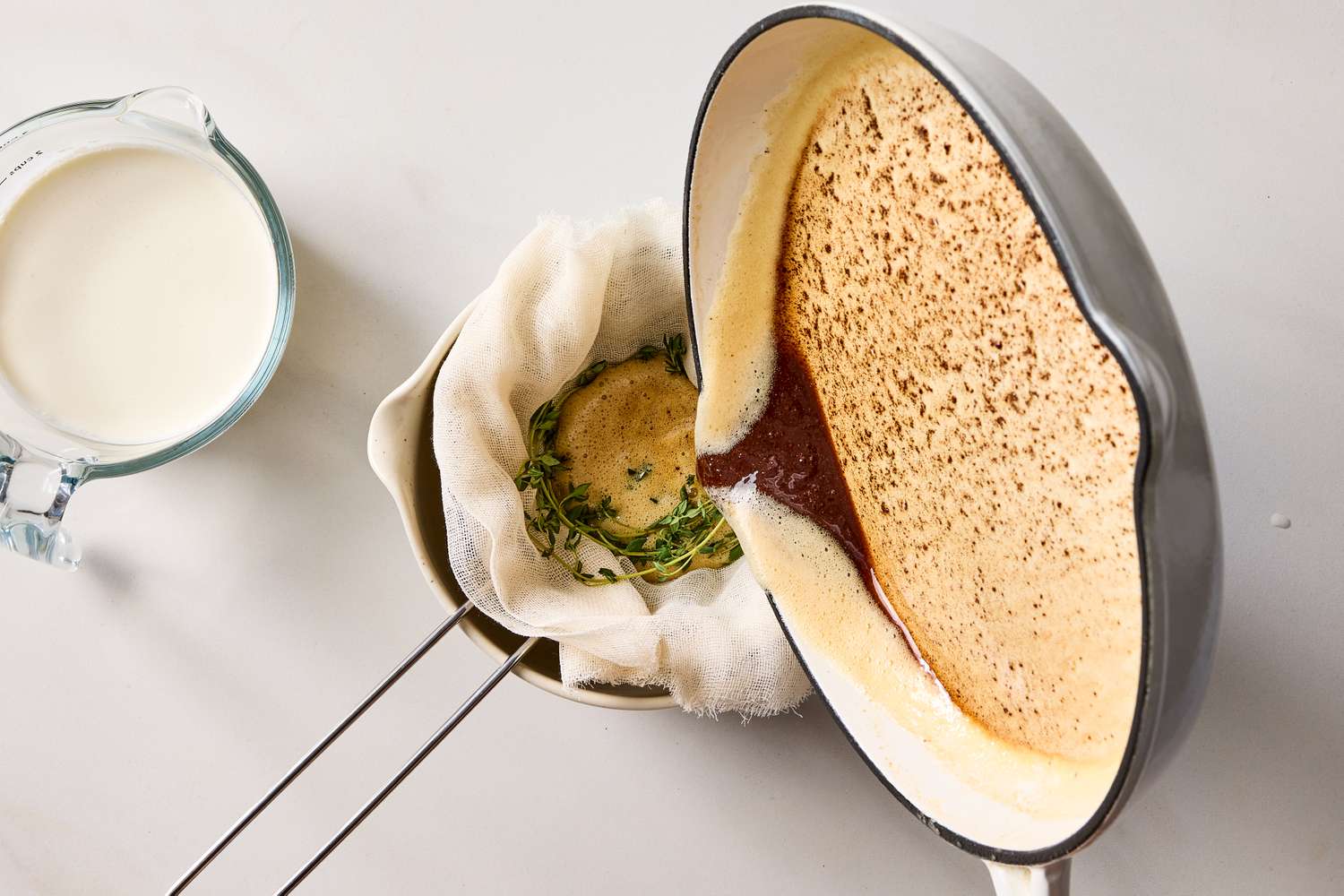 Brown butter being strained into a bowl lined with cheesecloth next to a jug of milk