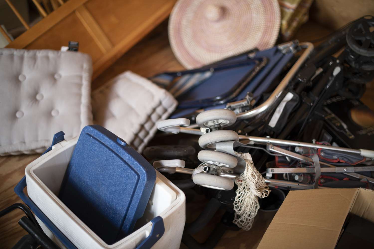 Various household items including cushions a walker and a cooler arranged in a cluttered space