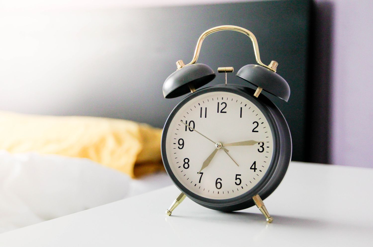 An alarm clock on a bedside table in a bedroom setting