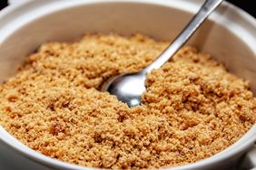 close up view of light brown sugar in white bowl with a spoon 