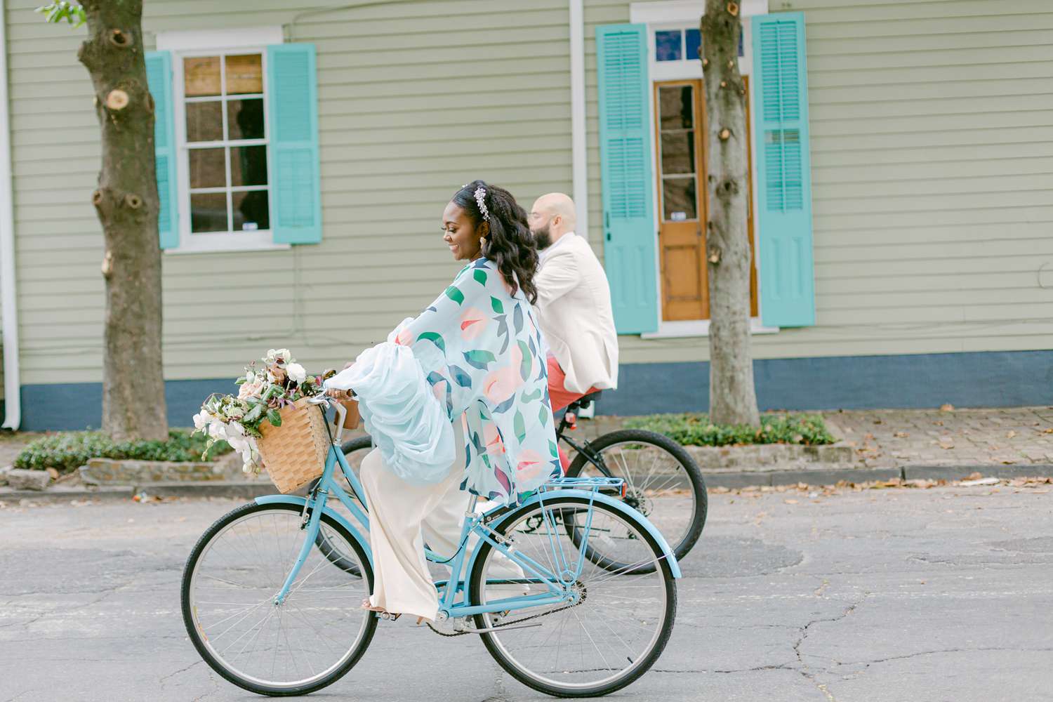 couple wearing pastels biking down street