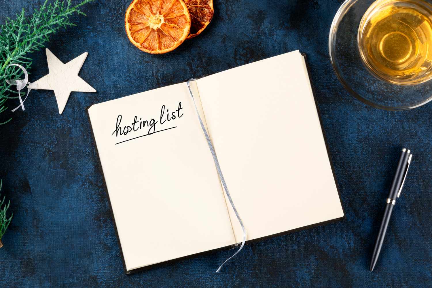 An open notebook with the title hosting list written on a page surrounded by decorative items and a pen