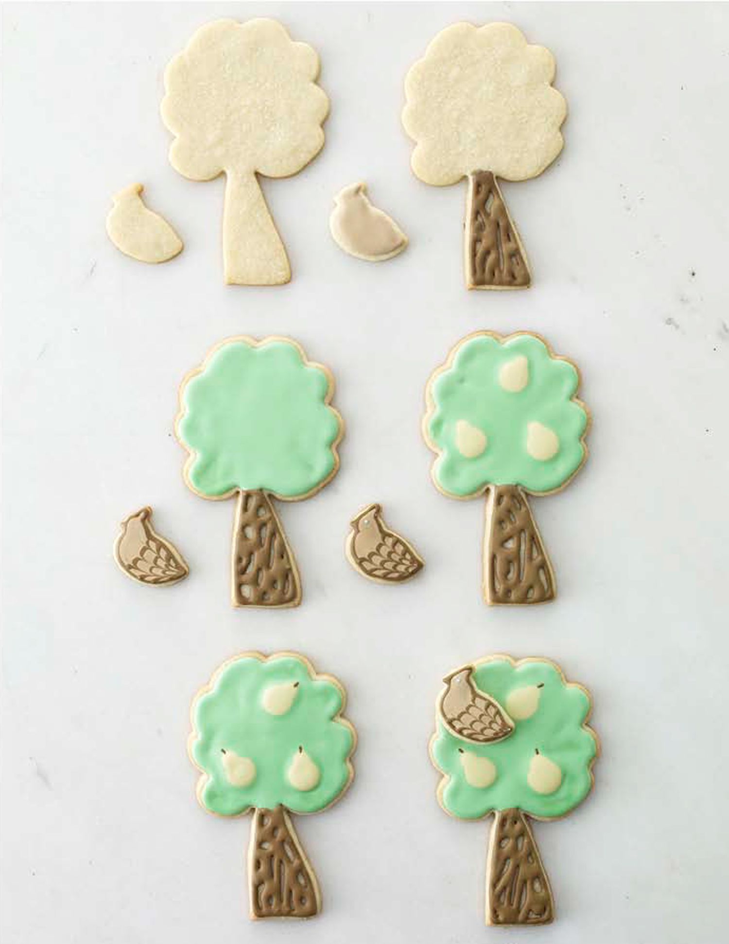 Progression of treeshaped cookies from raw dough to decorated with icing and details