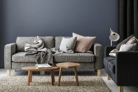 A modern living room with a sofa throw blankets cushions two wooden coffee tables and a floor lamp