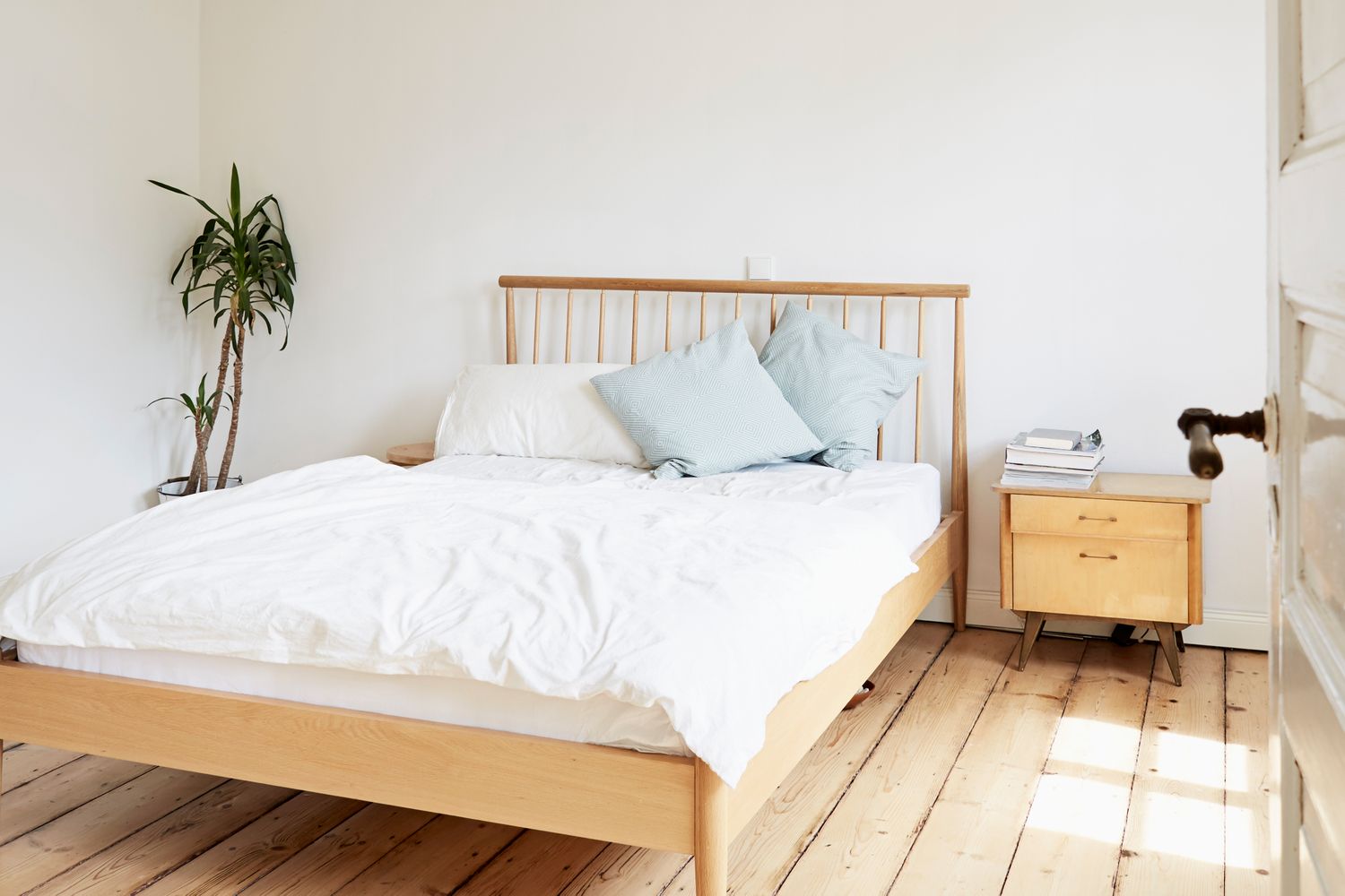 Simple bedroom with a bed bedside table and a potted plant