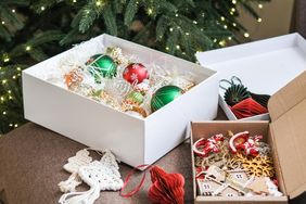 Christmas ornaments and decorations in open boxes near a decorated tree