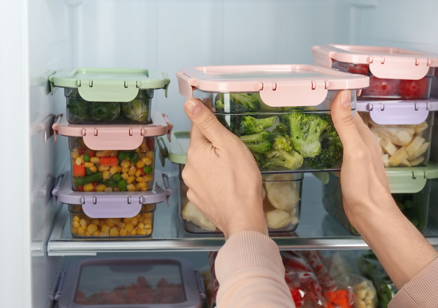 Woman taking container with broccoli from refrigerator
