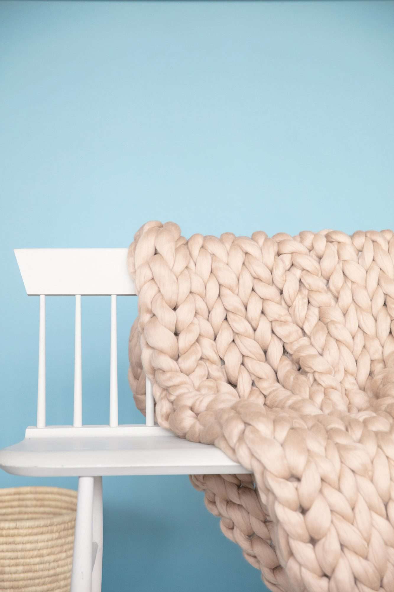 completed arm knit blanket folded over white bench