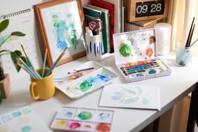 Art supplies and watercolor paintings on a desk