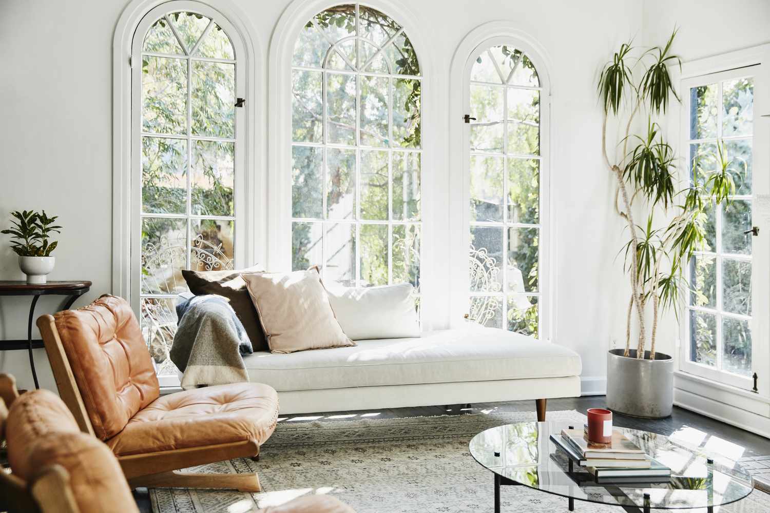 A welldecorated living room with arched windows a chaise lounge and plants