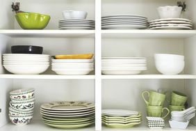 Tableware placed on a wooden shelf. Closeup of plates and dinnerware in a cupboard.