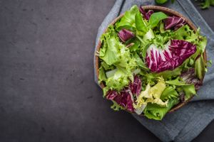 A bowl of mixed salad leaves on a fabric surface
