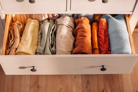 A neatly organized drawer with rolled clothing arranged by type or color