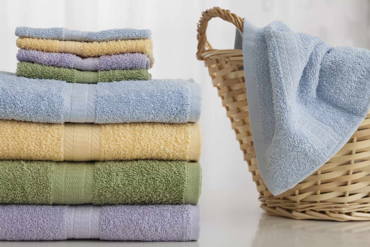 Stack of folded towels next to a basket with another towel draped over it