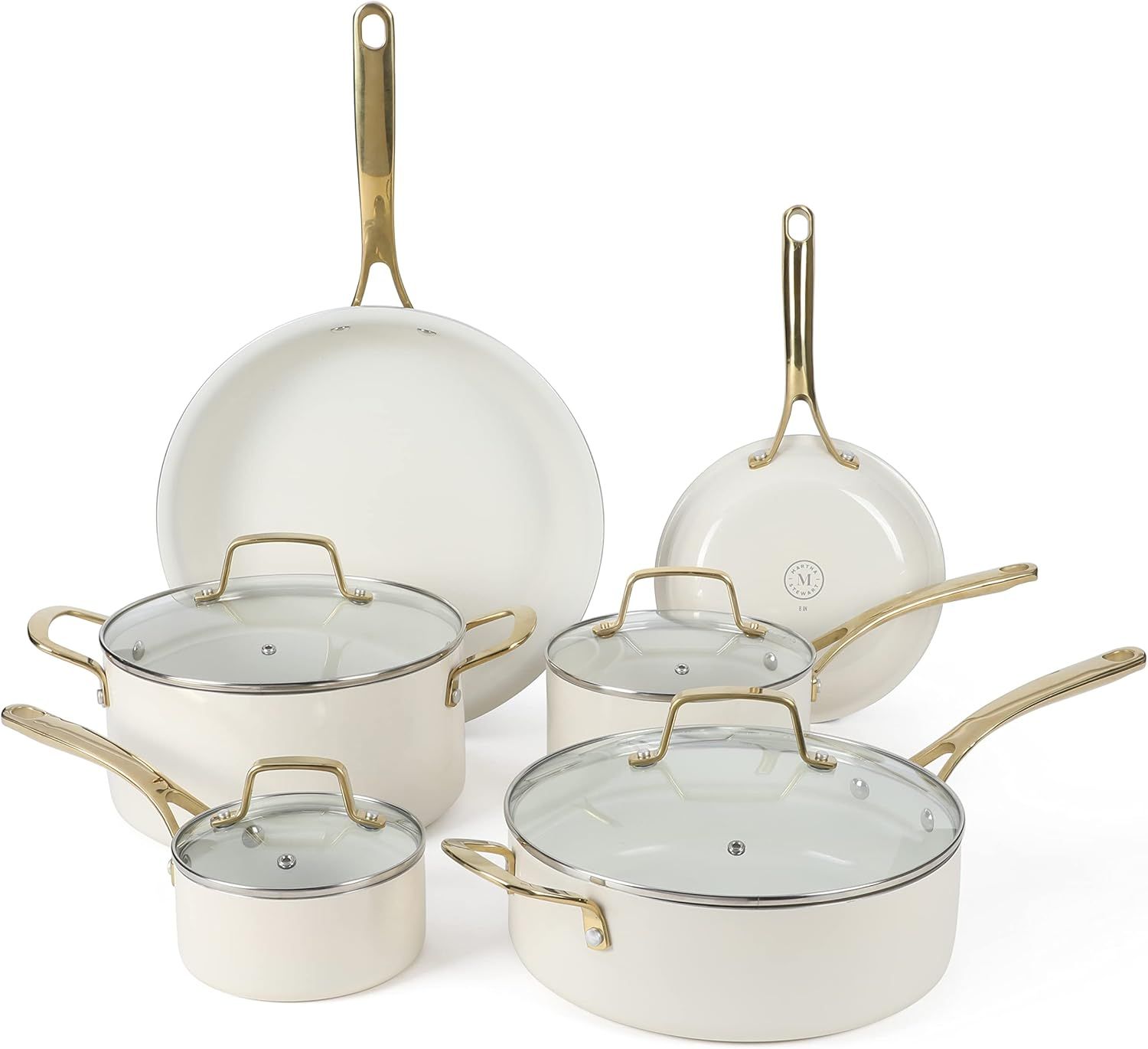 Set of creamcolored cookware with gold handles and glass lids including skillets and pots in various sizes