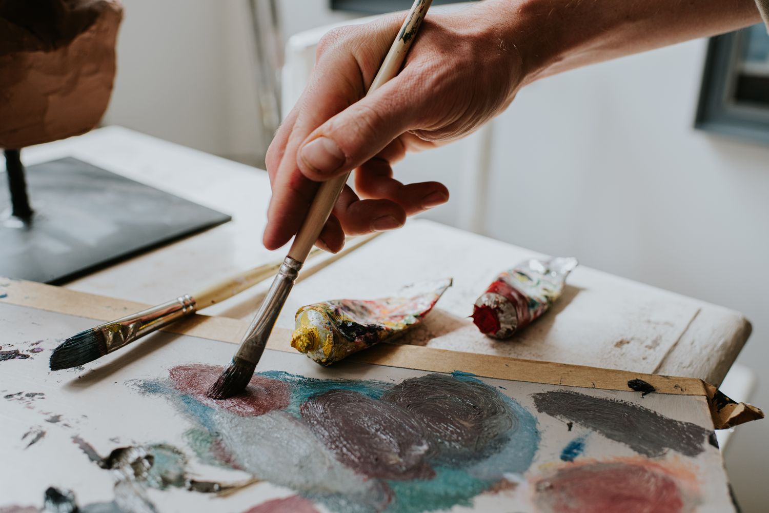 Hand holding paintbrush on canvas