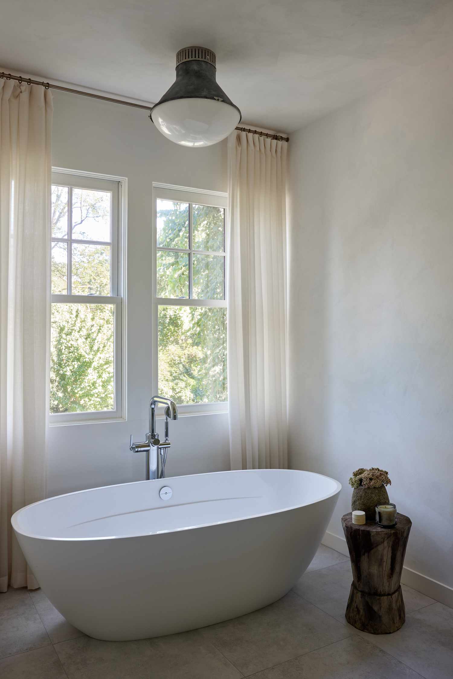 Modern bathroom with a freestanding tub, large windows, and neutral design elements
