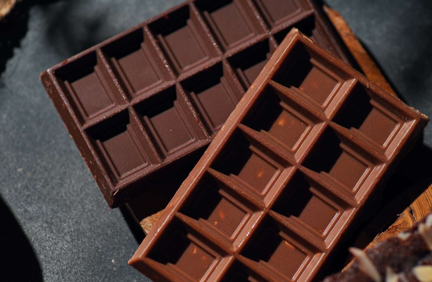 Two chocolate bars arranged on a dark surface