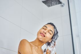 Shot of a young woman washing her hair with shampoo in the shower at home