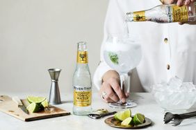 tonic water being poured into glass filled with ice