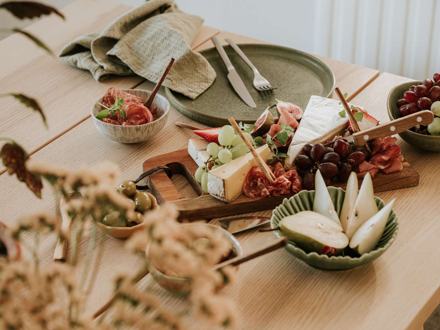 Assorted food items including cheese, fruit, and meat on a table setting