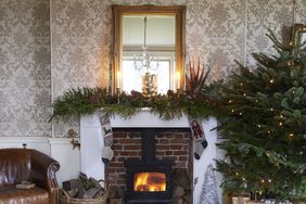 Fireplace decorated with garland and stockings Christmas tree with presents in a living room